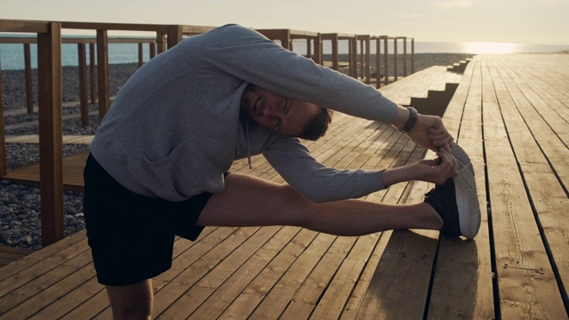 日落时分，年轻的运动员在户外做伸展腿的运动视频下载