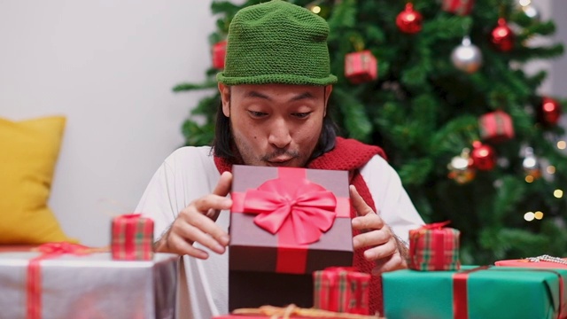 特写快乐的年轻亚洲人打开和惊喜的圣诞礼物，礼盒在庆祝派对，慢镜头视频下载