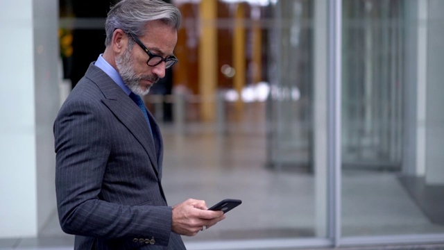 严肃的男企业家穿着昂贵的西装在手机里聊天的慢动作效果，视频素材
