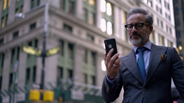 穿着豪华西装的成功男性商人用智能手机前置摄像头和电话应用程序进行视频通话视频素材