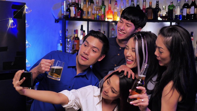 亚洲朋友在酒吧里用智能手机自拍。视频下载