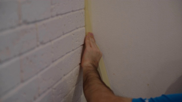 一个男人准备了一堵墙来画画。4K胶带贴视频下载