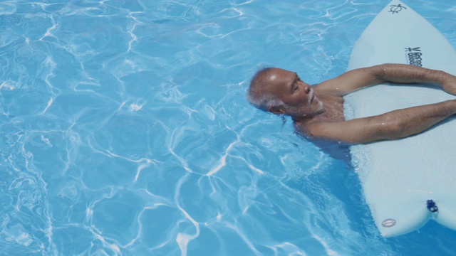 带着冲浪板漂浮在水面上的老人视频素材