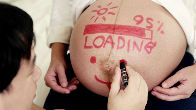 一名男子在孕妇的肚子上作画视频素材
