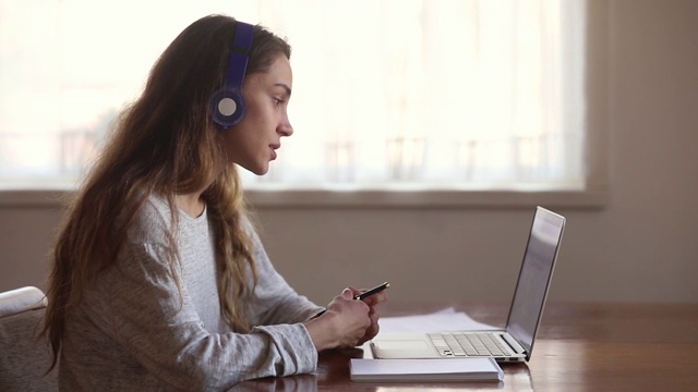 认真的女生戴着耳机和网络老师在线学习视频素材