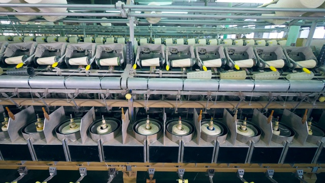 工厂的机器正在纺线。制衣厂生产设备。视频素材