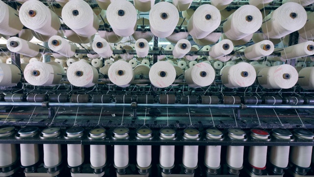 在纺织厂用带线轴的工业机器上进行裁剪的过程。视频下载