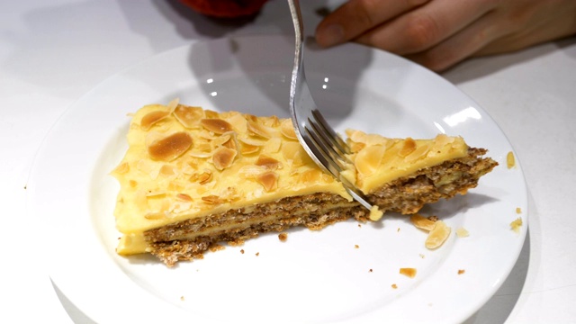 女人吃一块杏仁蛋糕与叉子在一个白色盘子上特写视频下载