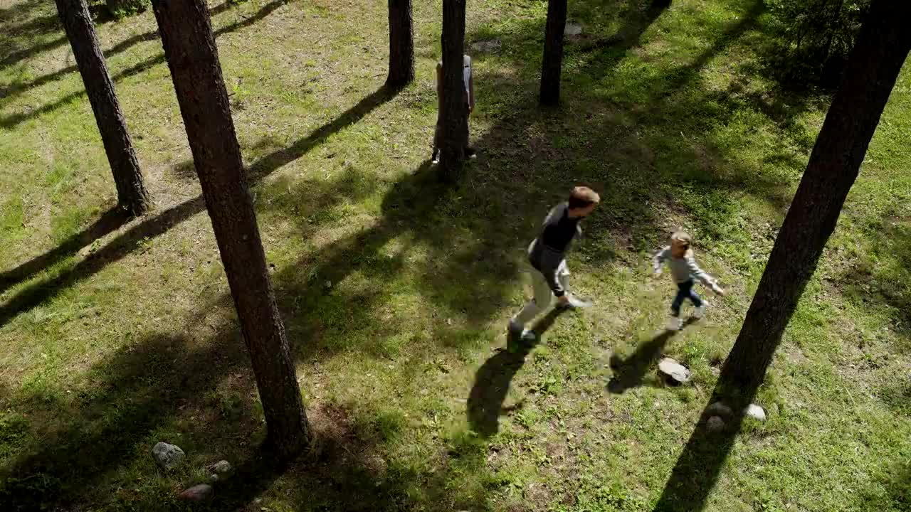 俯视图，快乐的家庭，父母和女儿一起在公园里玩捉人游戏，奔跑和躲在树干后面视频下载