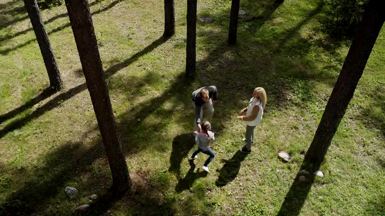 从上面的视角可以看到父母和女儿在森林里玩捉人游戏视频下载