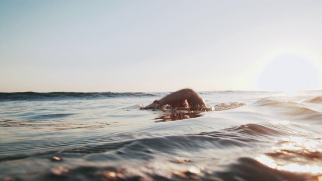 Slo Mo跟踪拍摄了一个在海里游泳的年轻人视频素材