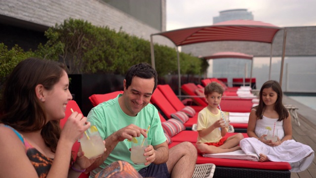 友好的服务员拿着柠檬水给幸福的家庭在屋顶酒店游泳池享受美好的一天视频下载