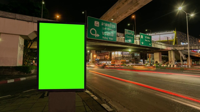 时间流逝，交通长曝光在道路与广告牌绿色屏幕用于广告的街道标志在城市。视频下载