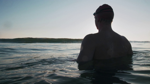日落时分，年轻男子在海里游泳视频素材