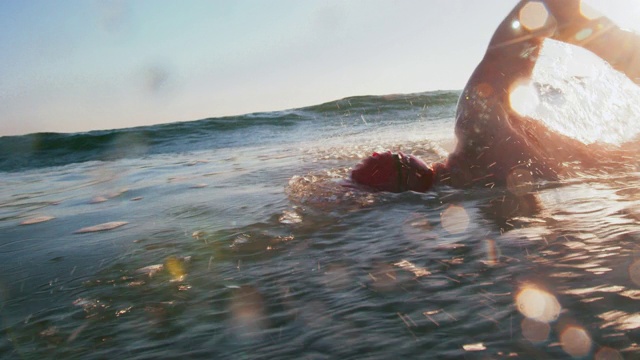 日落时分，一个年轻人在海里游泳视频素材