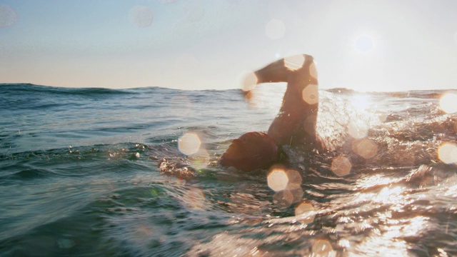 日落时，一个年轻人在海里游泳视频购买