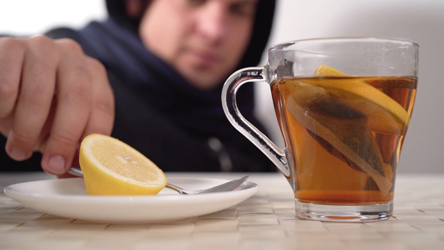 一个白人因为流感或感冒而擤鼻涕。喝红茶加柠檬作为一种自然疗法。视频素材