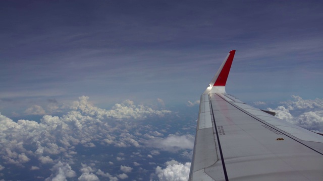 4K飞机的机翼在飞行旅途中与美丽的天空。飞机窗外的云朵视频素材