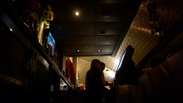 一个男人和一个女人站在一个灯光昏暗的酒吧里。视频下载