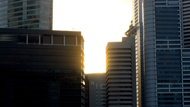 日落时分，城市天际线摩天大楼之间的太阳耀斑缓缓落下视频下载
