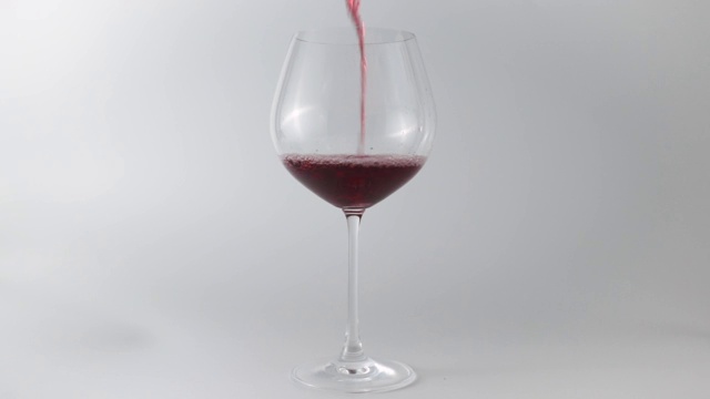 白色背景下的酒杯里的红酒视频素材