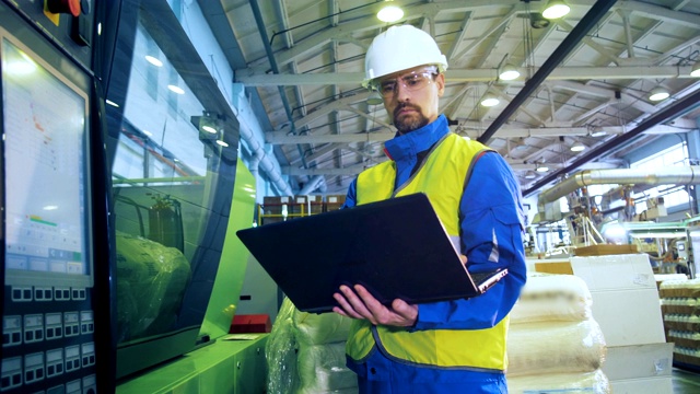 一位男性专家正站在控制面板附近操作一台笔记本电脑视频素材