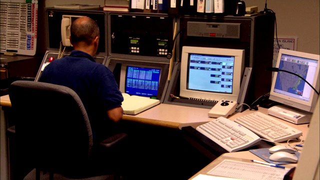 一个男人在一个装满电脑设备的控制室工作。视频素材