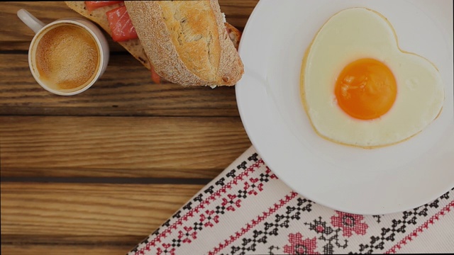 早餐供应:心形煎蛋，三明治和一杯咖啡视频素材