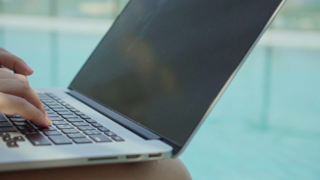 一个女人在泳池边用笔记本电脑的特写，慢镜头视频下载