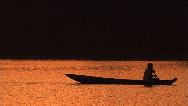 一个男人划着一条长长的独木舟。视频下载