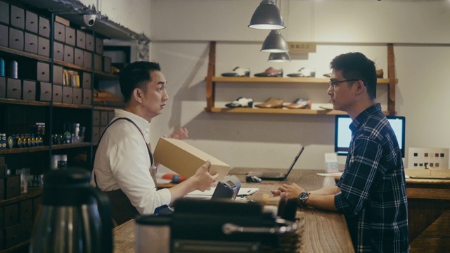 亚洲鞋店店员在柜台上与顾客交谈(慢镜头)视频下载