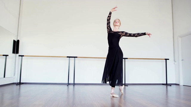 镜头的职业芭蕾舞女演员在黑色蕾丝紧身衣，长裹裙和尖头鞋表演舞蹈在芭蕾舞工作室视频下载