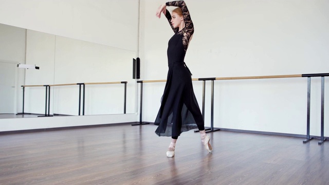 芭蕾舞女演员穿着黑色蕾丝紧身衣、长裹裙和尖头鞋在芭蕾舞舞蹈室排练舞蹈视频下载