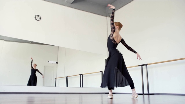 优雅的年轻芭蕾舞女演员在芭蕾舞工作室排练穿着黑色蕾丝紧身衣和长裹裙视频下载