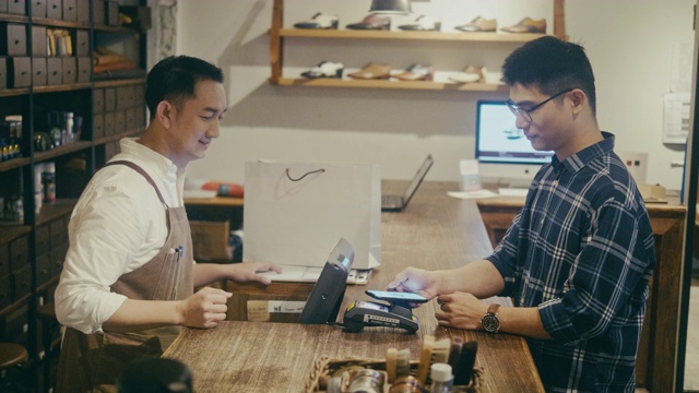 亚洲男人在男士精品店用手机付款(慢镜头)视频素材