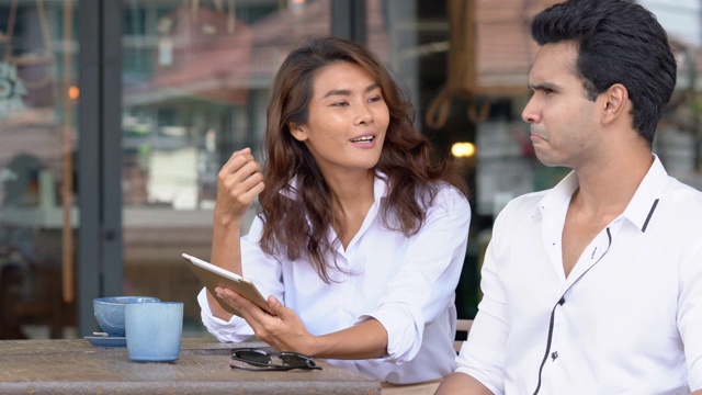 快乐的亚洲商人和女商人谈论和分享在咖啡店使用数字平板电脑和无线技术的商业想法4K媒体的镜头。户外办公理念。视频素材