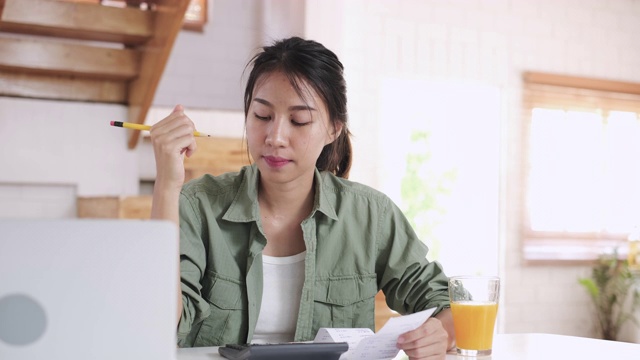 强调了亚洲女性在新房厨房餐桌上计算家庭财务账单预算时的严肃和争论视频下载
