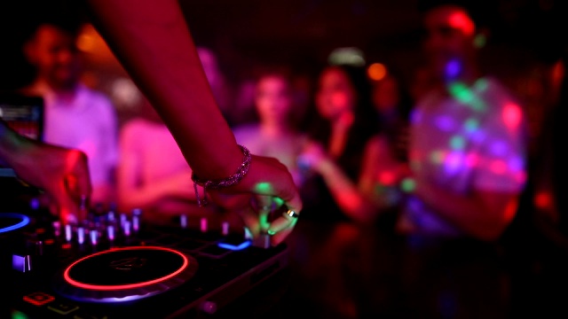 女DJ双手混音在唱盘上与年轻人跳舞的背景。她跳霹雳舞的时候舞厅里都是人视频素材
