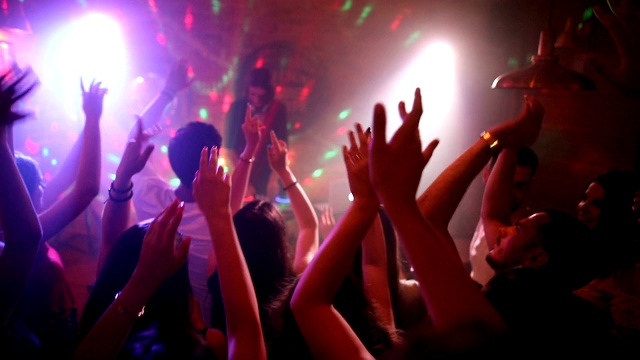 快乐的朋友与美丽的女DJ在舞台上举起手臂跳舞迪斯科视频素材