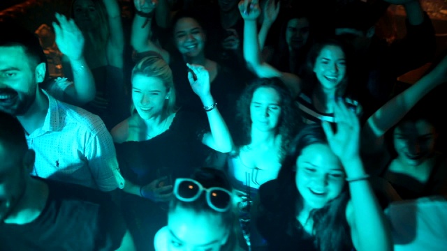 朋友们在迪斯科俱乐部玩得很开心。在夜总会人群跳舞。年轻人举起手臂跳舞视频素材