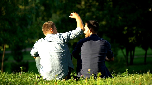 男人拥抱朋友，在阳光公园享受闲暇时光，背景，在一起视频素材