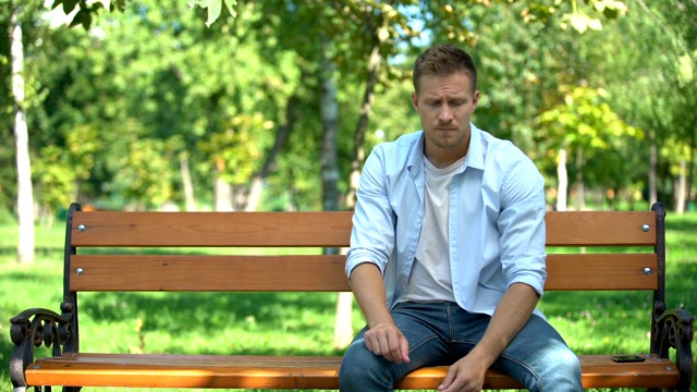 一个女人把伤心的男友独自留在公园的长椅上，然后离开，分手了视频素材
