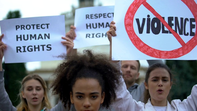 美国黑人女孩举着“禁止种族主义”的牌子，激进分子高喊着人权口号视频素材