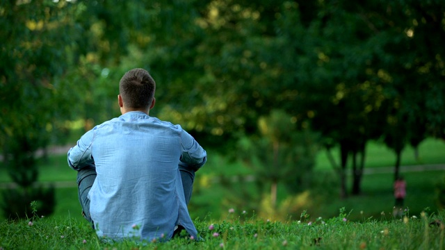 一个人坐在公园的草地上，在寂寞中享受周末视频素材