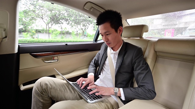 4K年轻商人在汽车后座上使用笔记本电脑视频素材