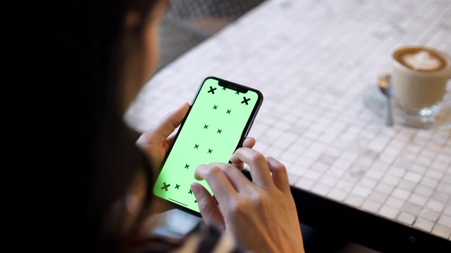 年轻女子用绿色屏幕的智能手机交流视频素材
