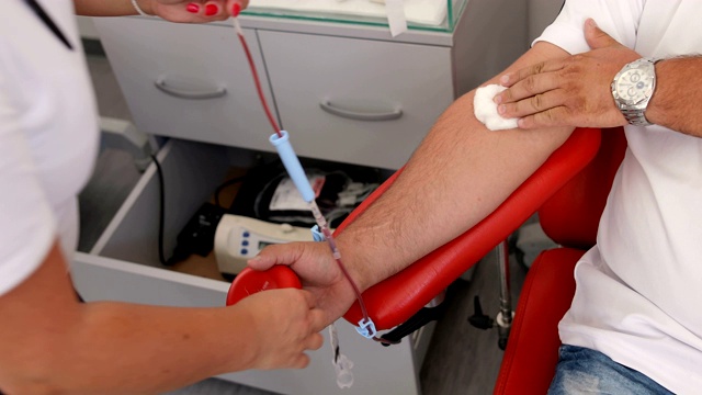 护士从捐赠者的手上取下医用针头。好事。为身体献血的好处。接受输血者的手。献血者在医疗诊所献血的特写视频下载