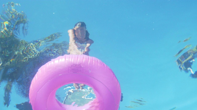 SLO MO年轻女孩跳水通过一个充气环进入游泳池视频下载