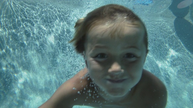 一个小男孩在游泳池里跳跃的水下镜头视频素材