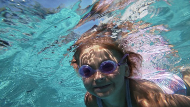 小女孩在游泳池的水下游泳视频素材